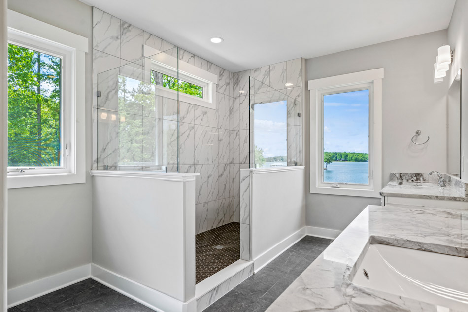 An elegant looking bathroom with a wagon wheel chandelier, tiled flooring, and shower backsplash installed with victorian pattern designed tiles