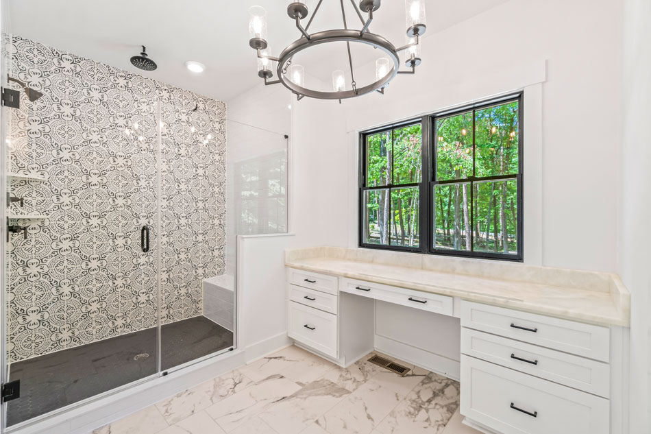 A newly remodeled bathroom with installed tile shower backsplash, newly painted walls, and glossy finish marble countertops